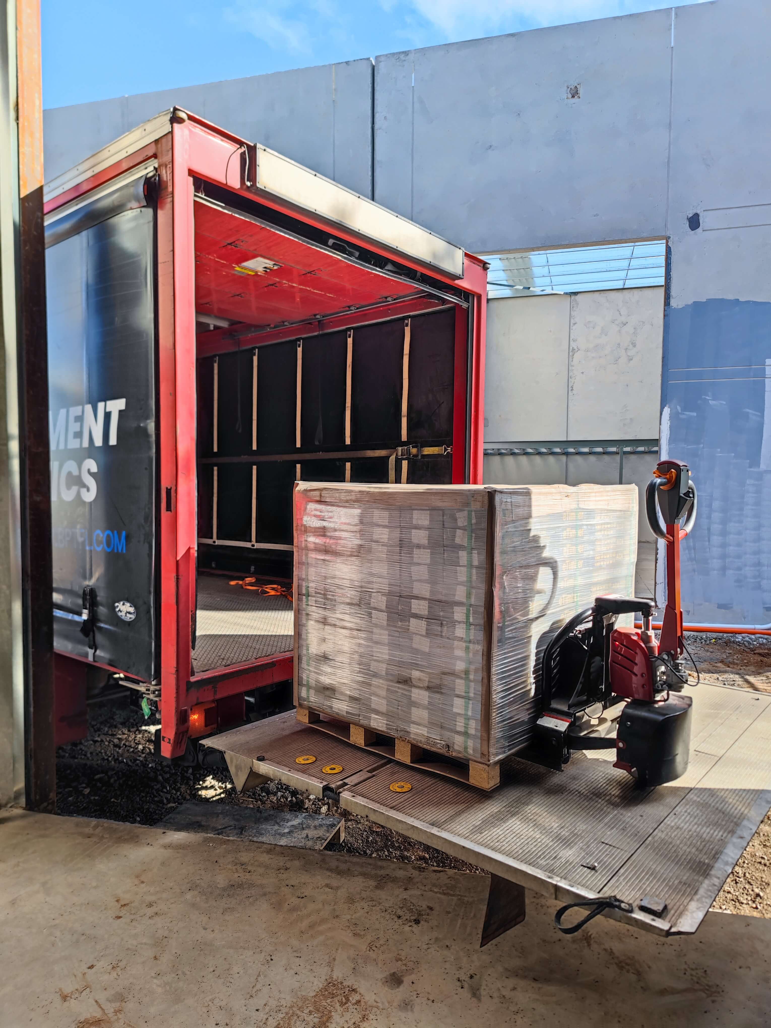 Palletised flooring delivered by a BPT Fulfilment branded red truck